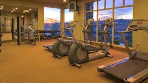 A gym with treadmills, exercise bikes, and weight machines, large windows with a view of the city, and a carpeted floor. - 485 Rooftop Hot Tub - Sleeps 24 (Hurricane)