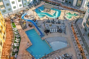 Un área de piscina en la azotea con varias piscinas, toboganes y sillones de descanso.