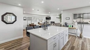 A modern kitchen with a large island, wooden flooring, and a dining area with a sofa and chairs. - 539 Massive 3 Bedroom Sleeps 10! (Yakima)
