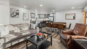 A modern living room with a sofa, coffee table, and dining area. - 539 Massive 3 Bedroom Sleeps 10! (Yakima)