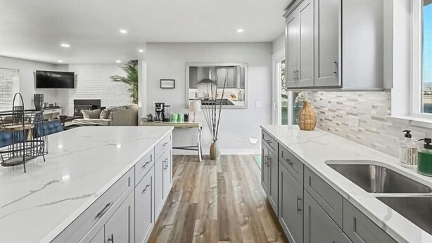 A modern kitchen with grey cabinets, a large island, and a dining area with a sofa and coffee table. - 539 Massive 3 Bedroom Sleeps 10! (Yakima)