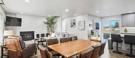 Un comedor moderno con una mesa de madera y sillas de cuero, un televisor y una chimenea.
