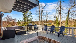A wooden deck with outdoor seating, including a sofa and chairs, and a hot tub.