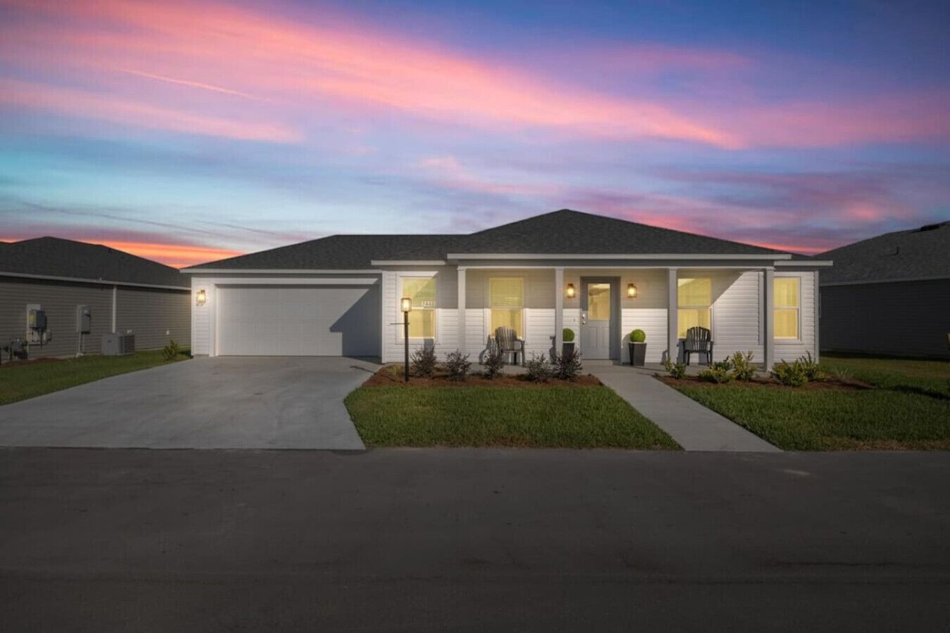 A single-story house with a garage, a front porch with chairs, and a well-maintained lawn.