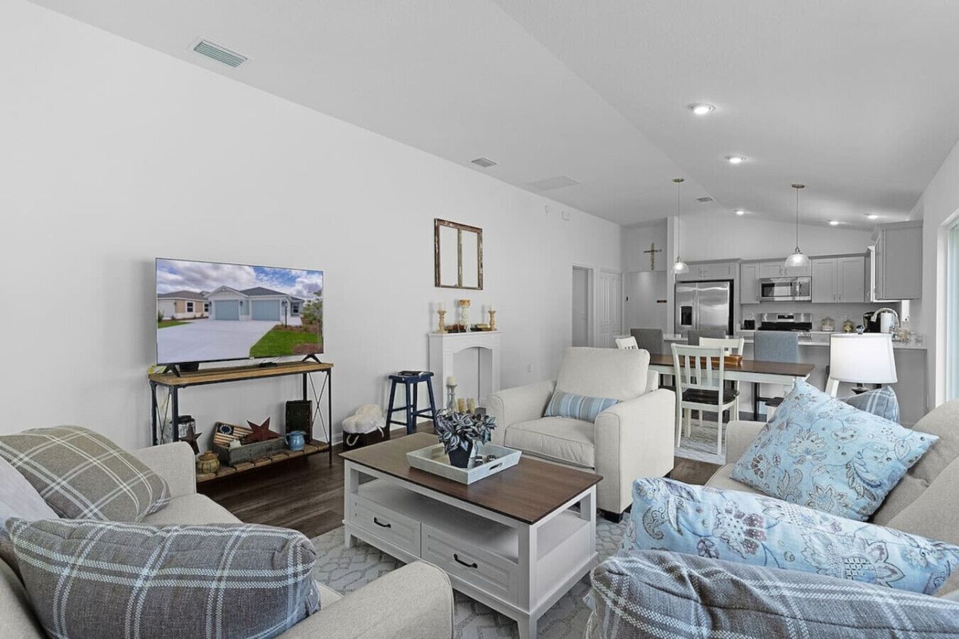 A modern living room with a television, a fireplace, and a dining area with a kitchen in the background.