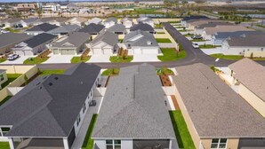 A residential area with modern houses, a central road, and a body of water in the background. - 561i Golf Cart Pool Access Garage Parking (Wildwood)
