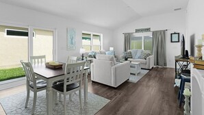 A spacious living area with a dining table, white furniture, and a view of the outdoors. - 561i Golf Cart Pool Access Garage Parking (Wildwood)