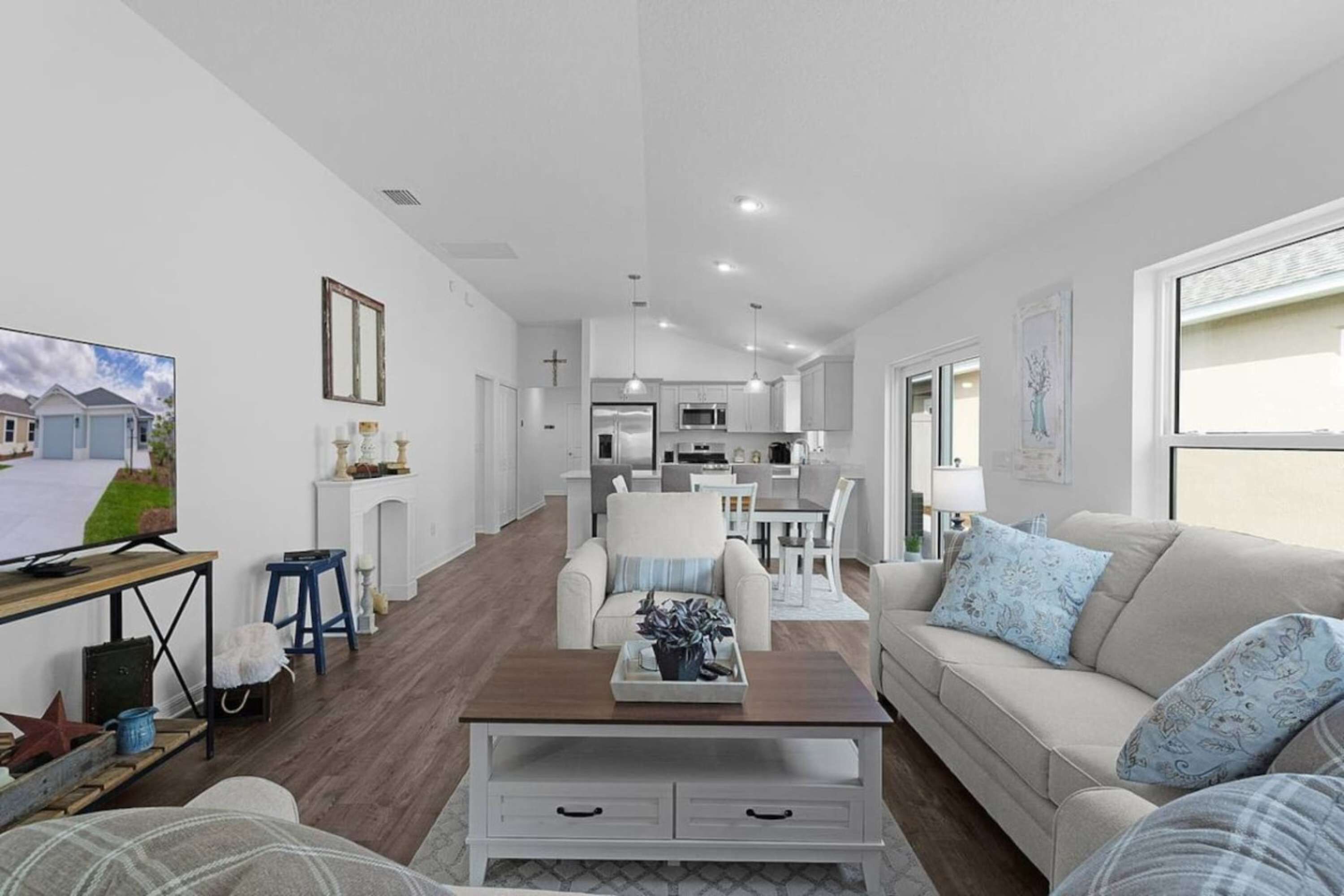 A modern living room with a sofa, coffee table, TV, and a kitchen in the background.