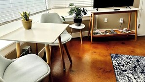 A living room with a TV, a dining table, chairs, a small round table with a plant, and a bookshelf. - Ground-floor gem Walk to it all (Roanoke)