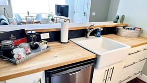 A modern kitchen with a dishwasher, a sink, and a countertop with jars and a coffee maker. - Ground-floor gem Walk to it all (Roanoke)