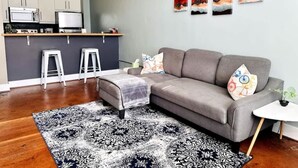 A modern living room with a grey sofa, a patterned rug, and a small white table with a plant. - Ground-floor gem Walk to it all (Roanoke)