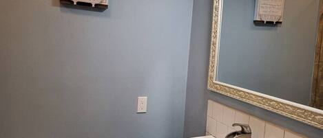 Ein Badezimmer mit Toilette, Waschbecken und Spiegel. An der Wand befindet sich ein Schild mit Reinigungshinweisen.