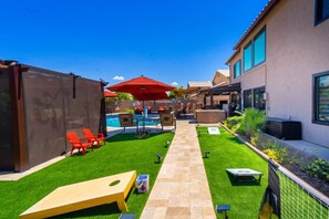 A backyard with a pool, red chairs, a wooden table, and a covered patio area. - 647 5 Bedrooms Hot Tub Firepit BBQ Kitchen (Glendale)