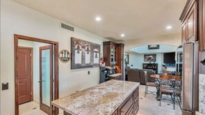 A kitchen with a granite countertop, wooden cabinets, and a dining area with a table and chairs. - 647 5 Bedrooms Hot Tub Firepit BBQ Kitchen (Glendale)