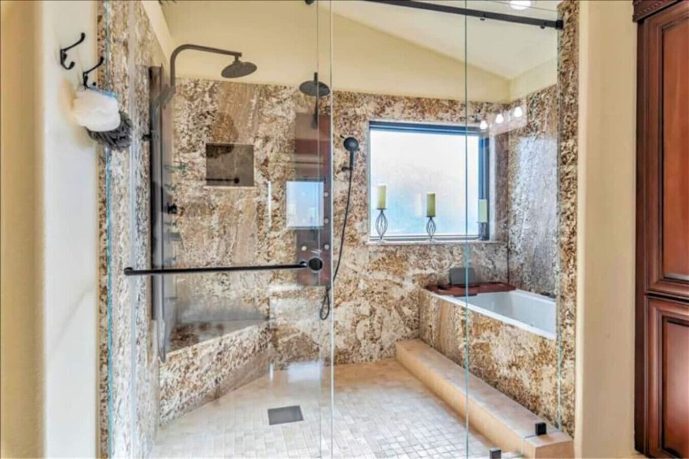 Une salle de bain avec une douche à parois de verre, une baignoire et une fenêtre décorée de bougies.
