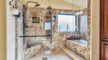 Une salle de bain avec une douche à parois de verre, une baignoire et une fenêtre décorée de bougies.