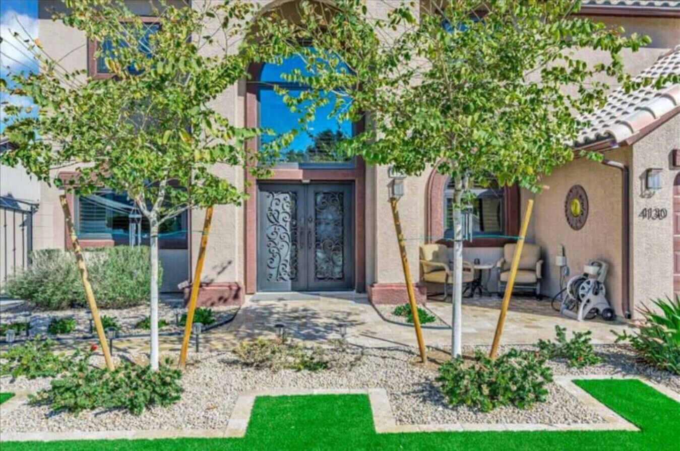 Un bâtiment doté d’une entrée centrale, entouré d’un jardin avec des arbres et une pelouse.