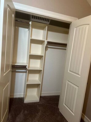 A walk-in closet with white shelving and a vent above. - 641 4 Bedrooms Luxurious Baths Open Living (Houston)