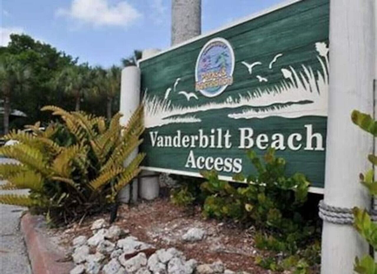 A sign for Vanderbilt Beach Access with a logo and decorative elements.