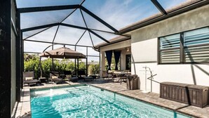 Ein Swimmingpool mit Glasveranda, Liegestühlen und einer überdachten Terrasse.