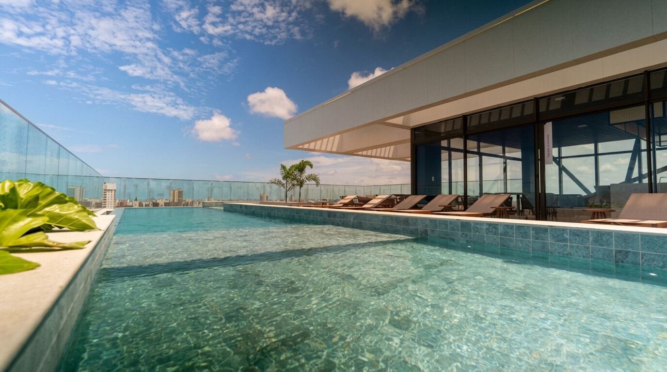 Piscina infinita moderna con agua cristalina, sillas de descanso y vistas a un horizonte urbano.