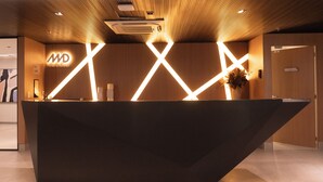 Un comptoir d’accueil au design moderne, agrémenté de motifs lumineux géométriques et d’un logo.