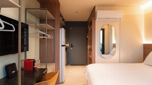 Une chambre d’hôtel comprenant un lit, un bureau avec un ordinateur, un miroir et une armoire.