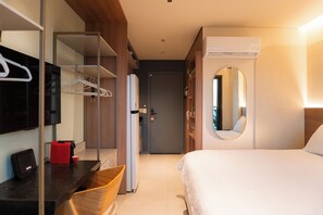 Ein Hotelzimmer mit Bett, Schreibtisch mit Computer, Spiegel und Kleiderschrank.