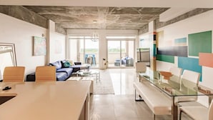 A modern interior with a glass table, seating, a sofa, and a colorful abstract wall. - Hang Ten- Large Townhome, lux Amenities, Parking (Miami)
