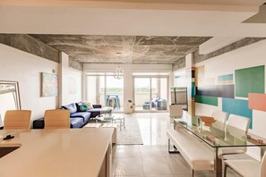 A modern interior with a glass table, seating, a sofa, and a colorful abstract wall. - Hang Ten- Large Townhome, lux Amenities, Parking (Miami)