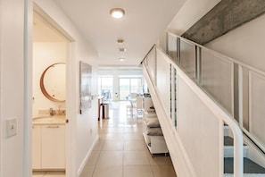 A modern interior with a staircase, a kitchen area, and a dining space. - Hang Ten- Large Townhome, lux Amenities, Parking (Miami)