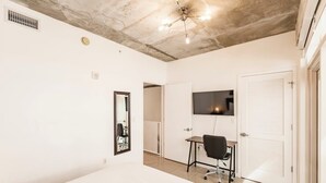 A bedroom with a bed, a desk, a chair, a TV, a door, and a ceiling fan. - Hang Ten- Large Townhome, lux Amenities, Parking (Miami)