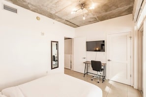 A bedroom with a bed, a desk, a chair, a TV, a door, and a ceiling fan. - Hang Ten- Large Townhome, lux Amenities, Parking (Miami)