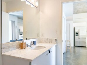 A modern bathroom with a marble countertop, a double sink, a large mirror, and a wooden soap dispenser. - Center Stage- Downtown, Parking, Pool, Hot Tub (Miami)