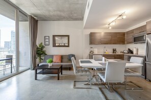 Um apartamento moderno com área de refeições, cozinha e uma janela grande com vista para a cidade.