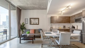 A modern apartment with a dining area, kitchen, and a large window with a city view.