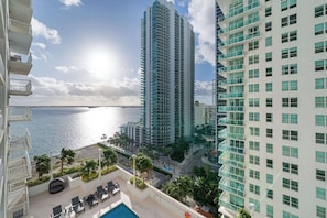 A high-rise building with a pool area, palm trees, and a view of the ocean. - Brickell Bay View- Unbeatable Location With Parking (Miami)