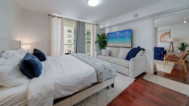 A bedroom with a bed, a sofa, a chair, a painting, and a plant. - Brickell Bay View- Unbeatable Location With Parking (Miami)