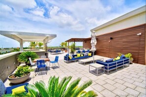 An outdoor patio area with seating, umbrellas, and potted plants.