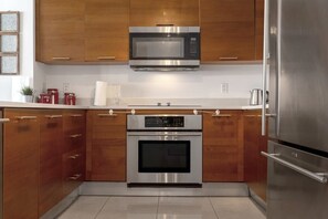 Une cuisine moderne avec des meubles en bois, des appareils en acier inoxydable et un plan de travail blanc.