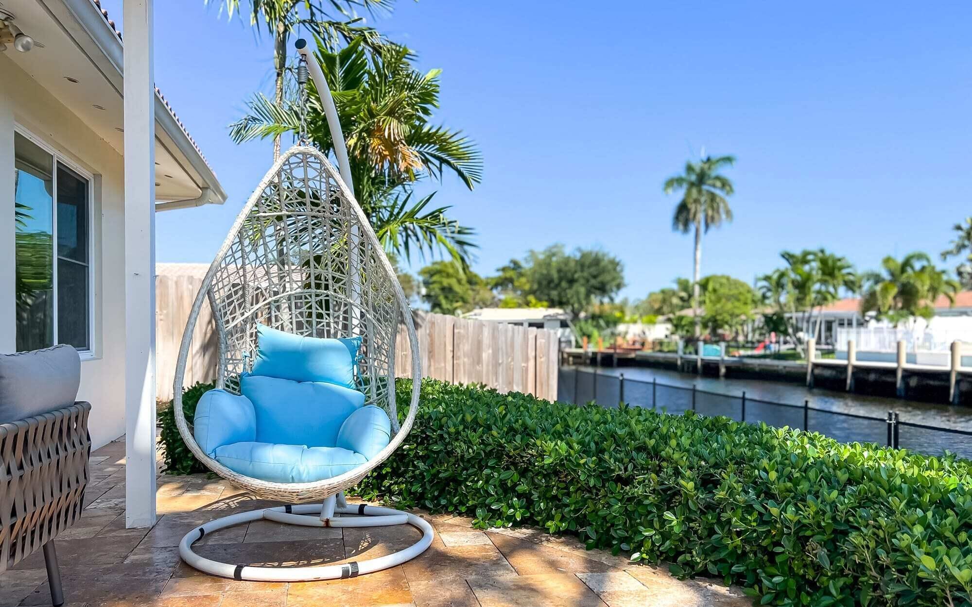 Una silla colgante con cojines, un patio con vistas a un cuerpo de agua y una cerca de madera.