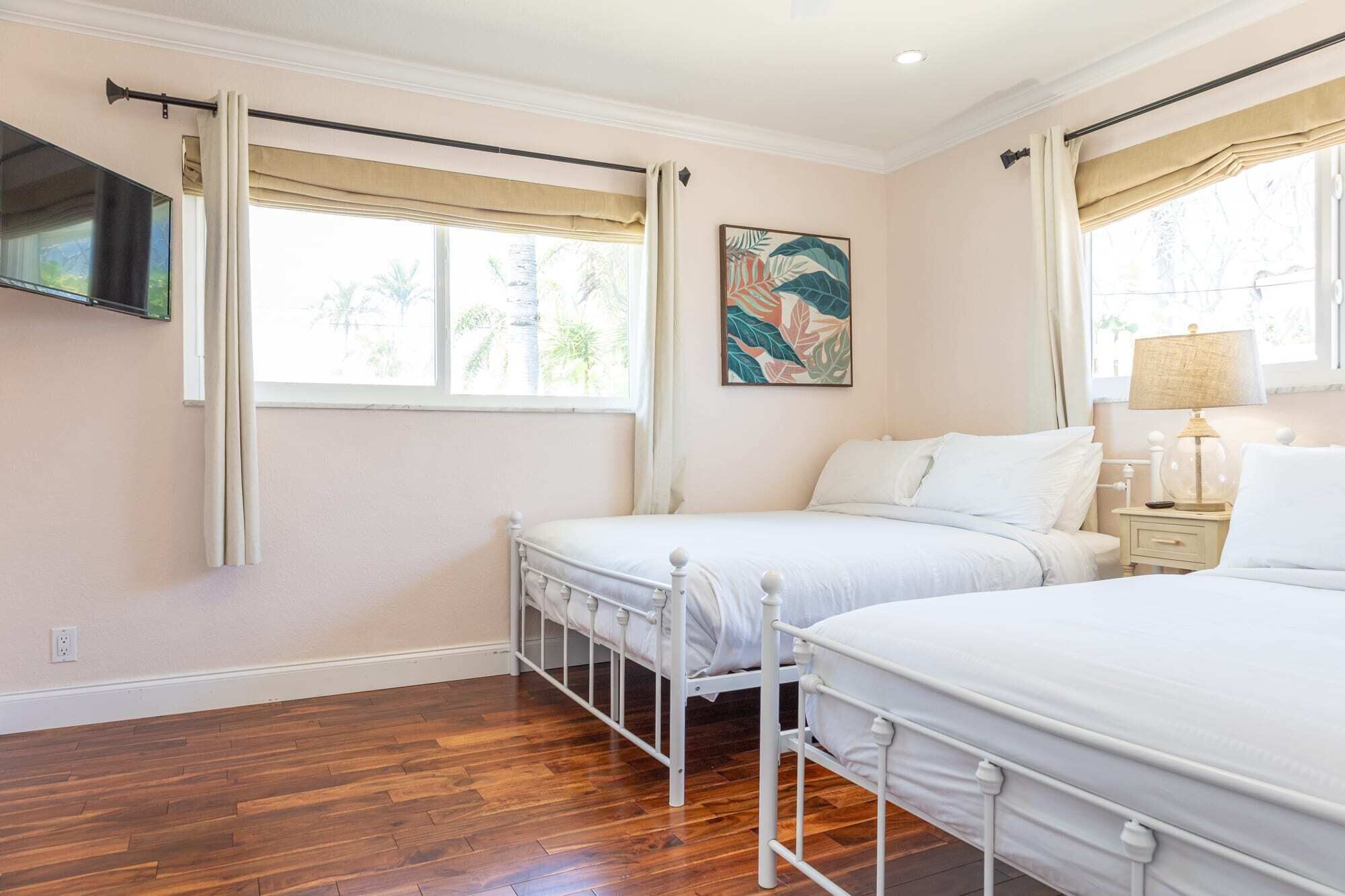 A bedroom with two beds, a TV, and a painting.