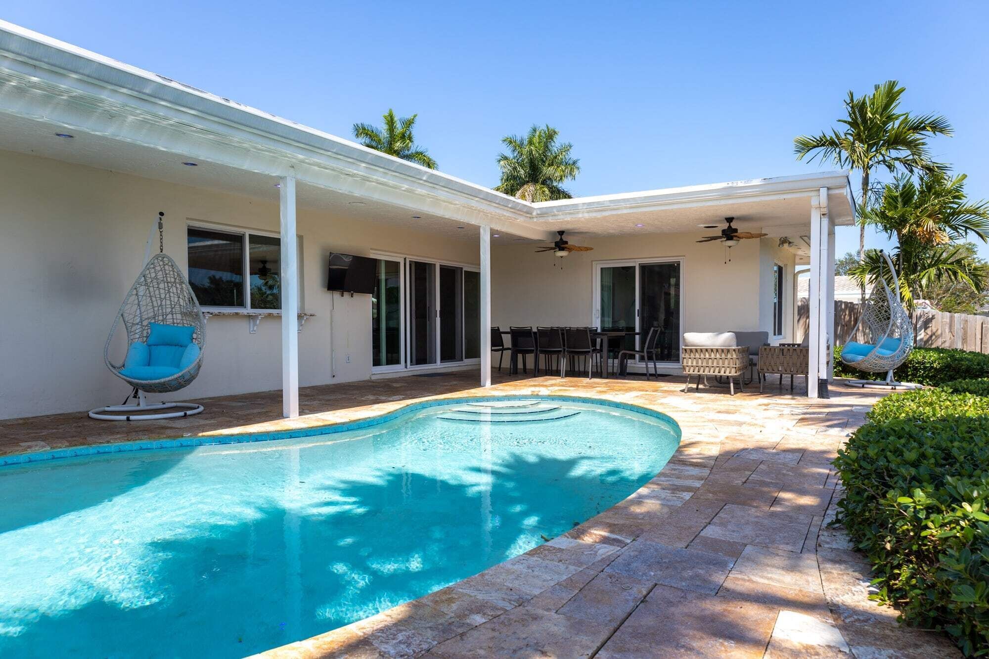 A swimming pool with a patio area, outdoor furniture, and a covered seating area.