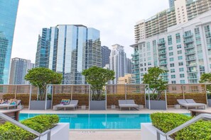 A rooftop pool with lounge chairs, surrounded by high-rise buildings. - Brickell House Dreams - Luxury Stay and Amenities (Miami)