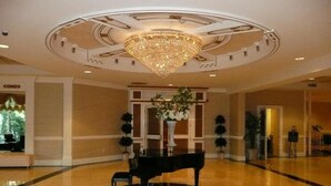 A spacious lobby with a grand chandelier, a piano, and a large vase with flowers. - Serene Stay With Amenities & Breakfast bar (West Orange)
