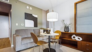 A modern living room with a sofa, two chairs, a round table, a floor lamp, a large abstract painting, and a wooden cabinet with decorative items. - Biscayne Bay Views-pool, Hot Tub and Amenities (Miami)