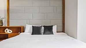 A bed with a wooden headboard, white bedding, and two black pillows. - Biscayne Bay Views-pool, Hot Tub and Amenities (Miami)