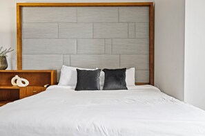 A bed with a wooden headboard, white bedding, and two black pillows. - Biscayne Bay Views-pool, Hot Tub and Amenities (Miami)
