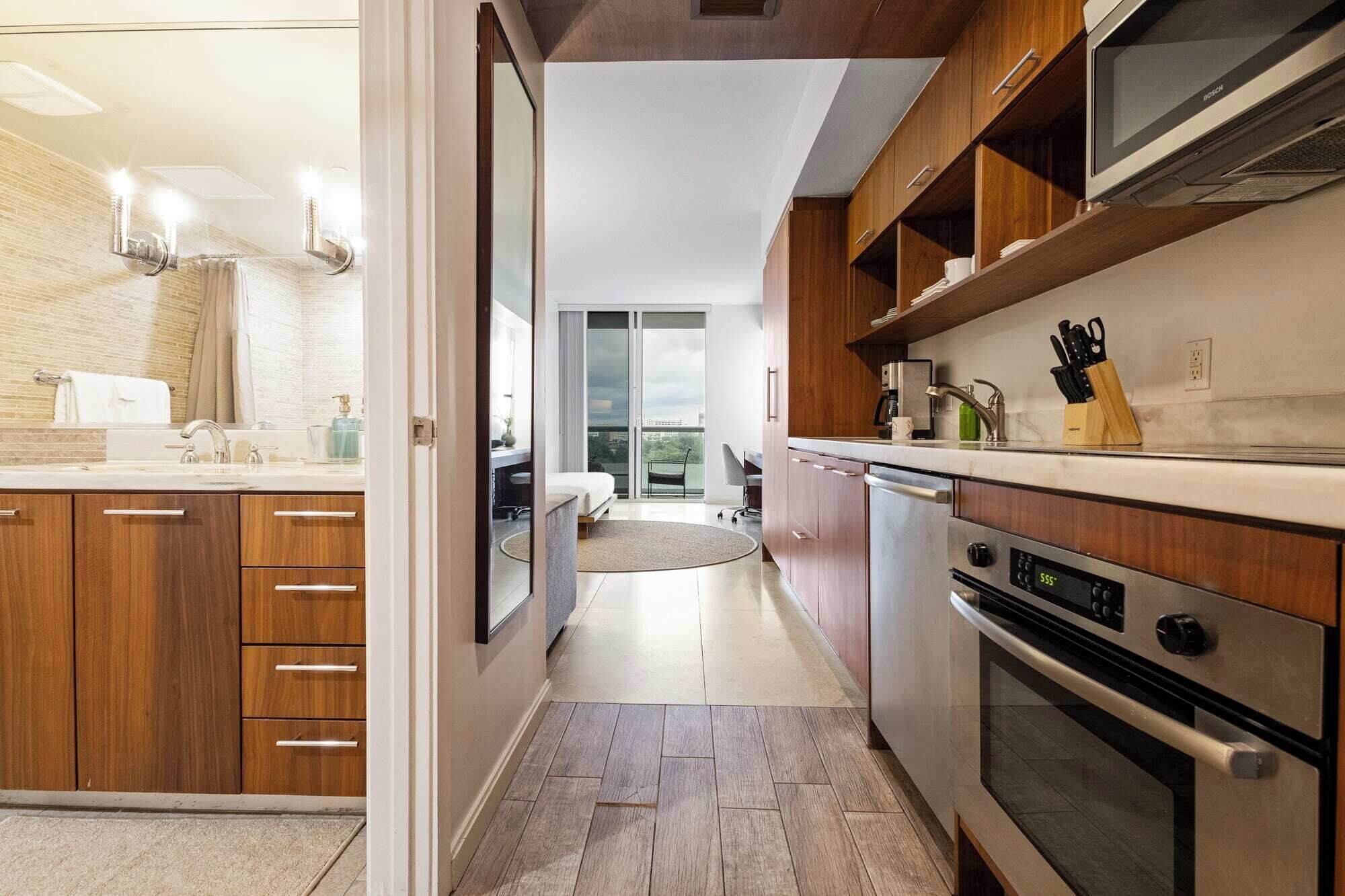 Eine moderne Küche mit Holzausstattung, einem Einbauofen und Blick auf einen Balkon.