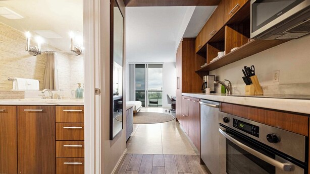 A modern kitchen with wooden cabinets, a built-in oven, and a view to a balcony. - Biscayne Bay Views-pool, Hot Tub and Amenities (Miami)